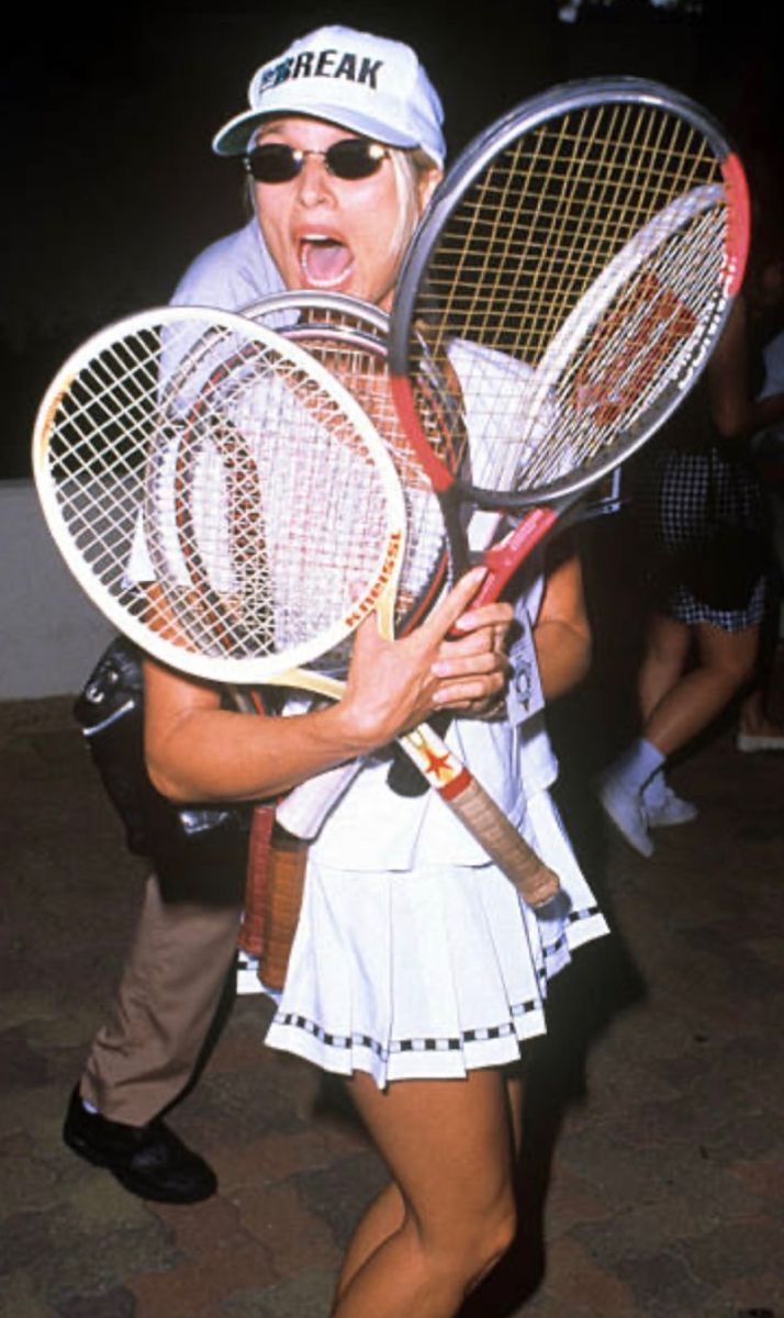 Arms full of mismatched rackets and a pleated skirt